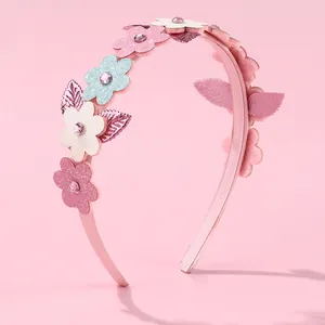 Détail d'un serre-tête rose avec fleurs pailletées et strass incrustés pour filles