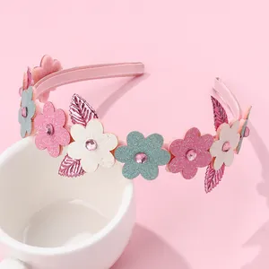 Serre-tête fleuri à paillettes avec strass roses sur un présentoir de tasse blanche