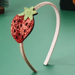 Close-up of golden glitter headband with a red and green sequin strawberry detail