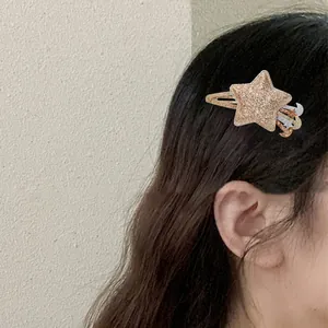 Détail d'une pince à cheveux pailletée étoile et lune avec pompon sur les cheveux