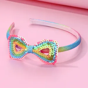 Rainbow gradient girls headband with sparkling sequined heart bow on a pink backdrop