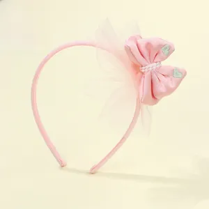Dettaglio del cerchietto rosa con fiocco ricamato a cuore e perle su rete morbida
