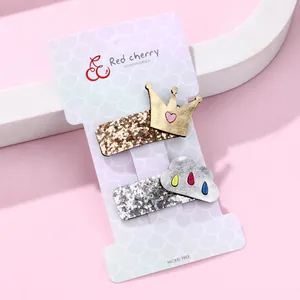 Detail view of two glittery crown and cloud hair clips on branded display card