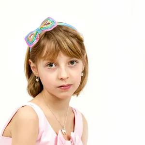 Detail of a young girl wearing a light blue headband with a large rainbow sequin bow