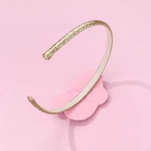 Detalle de diadema dorada brillante con lazo de fieltro rosa y forro interior antideslizante