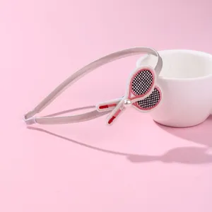 Detail of grey fabric headband with embroidered tennis rackets and a small pearl accent