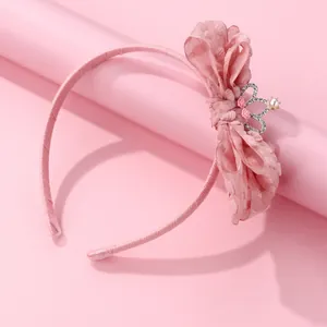 Pink fabric headband with polka dot bow and crown pearl accent on a pink background
