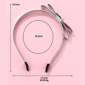 Detail view of silver PU bow headband with pearls and pink flower on a pink background