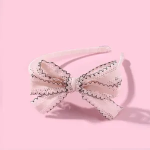 Detail van een roze kanten hoofdband met gelaagde stof en zwarte geschulpte stiksels