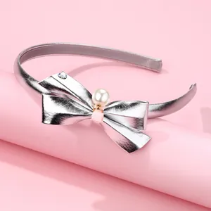 Detail of silver metallic bow headband featuring a central pearl and anti-slip inner lining