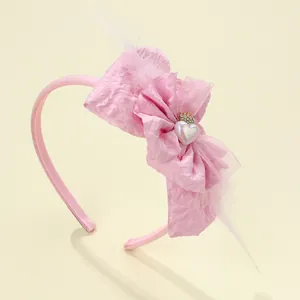 Detail of pink girls headband with bow, soft feathers, and a small golden crown accent