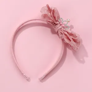 Detail of pink headband featuring large organza bow and rhinestone crown with pearl