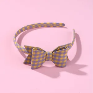 Sweet purple and yellow plaid fabric headband with a bow for girls on pink background