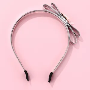 Detail of silver shiny PU headband with handcrafted bow and pearl-like sequin decoration