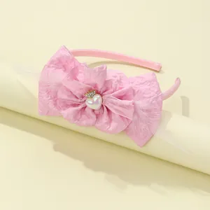 Detail of pink fabric bow headband for girls with white feathers and gold crown heart