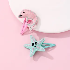 Dettaglio di fermagli in tessuto a forma di delfino rosa e stella marina per bambini