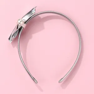 Detail of silver bow headband with white faux pearl and rhinestone on pink background