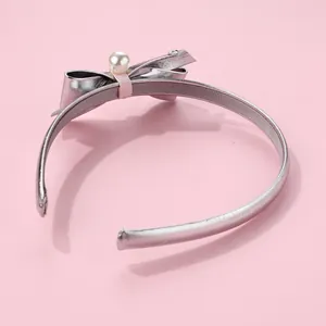 Detail of silver metallic headband with bow, faux pearl, and anti-slip velvet lining