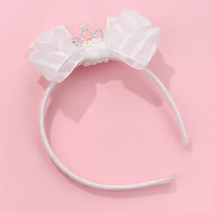 Detail of white organza bow headband with silver rhinestone crown and faux pearl accent