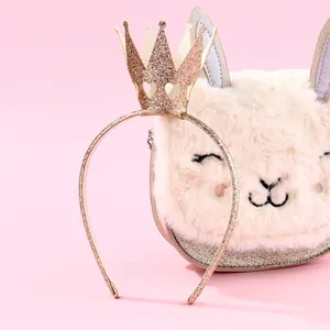 Detail of a sparkling gold glitter crown headband on a soft pink background with props