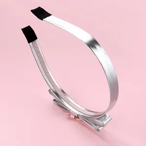 Detail of silver metallic PU bow headband with non-slip ends and shiny finish