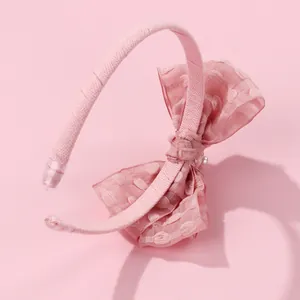 Close-up of pink organza bow headband with flocked polka dots and a center pearl detail