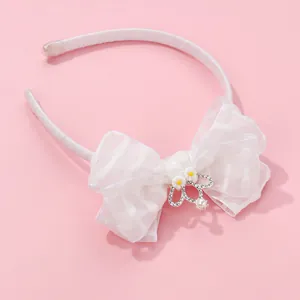Close-up of white organza bow headband with crown pendant and small daisy details