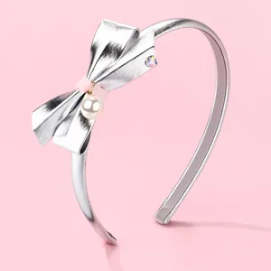Detail of silver headband with pink ribbon bow, white pearl pendant and tiny rhinestone