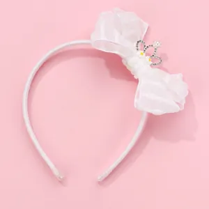 Detail of white organza bow headband with crown rhinestones and pearl on pink background
