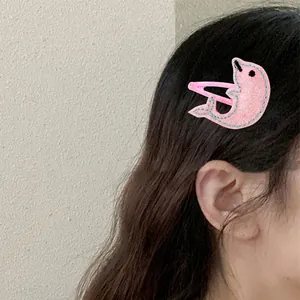 Dettaglio del fermaglio a delfino rosa glitterato con cucitura blu sui capelli