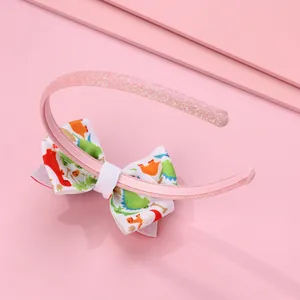 Dettaglio di cerchietto glitter rosa con fiocco a dinosauri e rivestimento antiscivolo