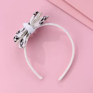 Détail du serre-tête pailleté avec nœud en ruban au motif ballon de football