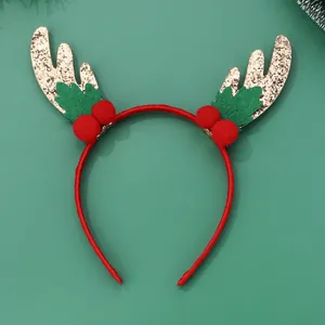Detail of Christmas headband with golden reindeer antlers and red pom-poms on green base