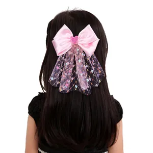 Détail d'un nœud en satin rose avec paillettes et tulle coloré sur les cheveux d'une fille