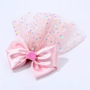 Détail d'une pince à cheveux nœud en satin rose avec voile en tulle pailleté et cœur