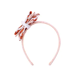Détail d'un serre-tête à paillettes roses avec nœud multicouche blanc et motif basket