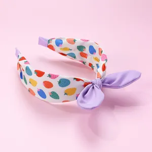 Détail d'un serre-tête doux avec imprimés fraises colorés et un joli nœud violet