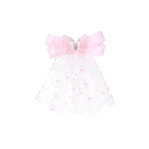 Détail de la pince à cheveux rose avec sequins, nœud en tulle et pierre rose
