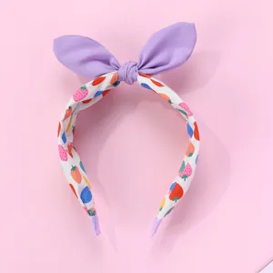 Détail d'un serre-tête oreilles de lapin avec motifs fraises et embouts violets