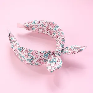 Detailed view of floral fabric headband with knot bow on a soft pink background