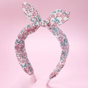 Detail of fabric knotted headband featuring pink and blue floral prints on white base