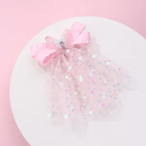 Détail de la pince à cheveux nœud rose avec papillon 3D, paillettes et pompons tulle