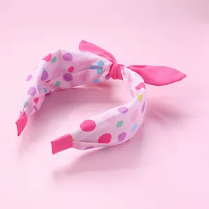 Détail du serre-tête rose à pois avec nœud et embouts de protection en tissu doux