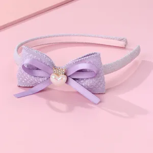 Détail d'un serre-tête nœud en tweed violet avec cœur en résine et couronne
