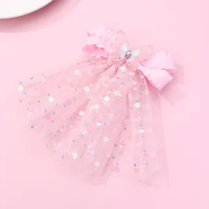 Détail d'une pince à cheveux en satin rose avec papillon brodé et tulle à paillettes