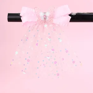 Détail de la pince à cheveux nœud rose avec papillon brodé et ruban à paillettes