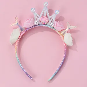 Detail of mermaid headband with glitter crown, shells, and flowers on pink background