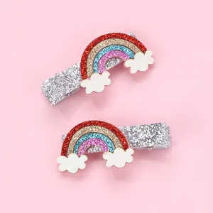 Detail view of glittery rainbow and cloud hair clips for kids on pink background