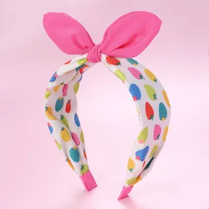Détail d'un serre-tête avec oreilles de lapin, imprimé fruits et tissu rose vif