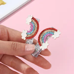Detailed macro of glittery rainbow cloud hair clips held by hand for scale
